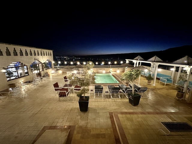 Night view of a hotel courtyard with a pool and seating.