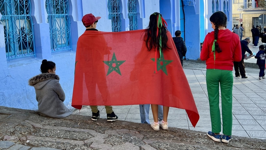 Children standing with a large red flag with stars.
