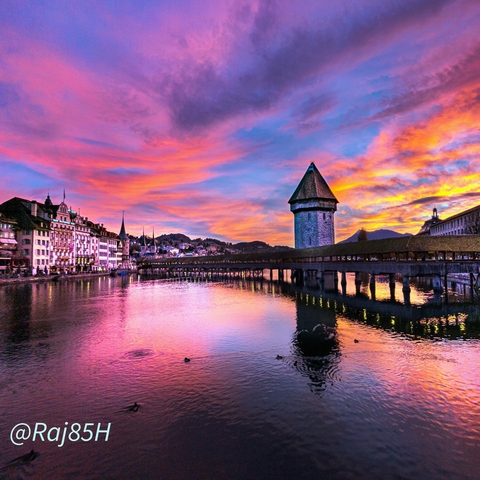 Lucerne Chapel Bridge with a colorful sky at sunset.