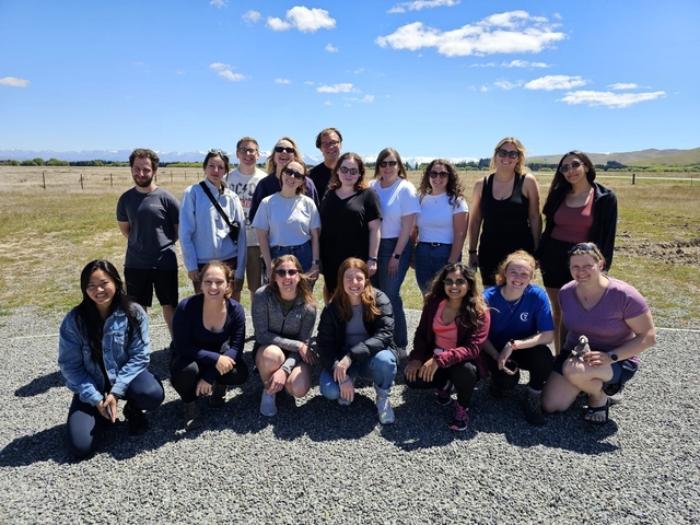 Group of people posing in an open field on a sunny day.