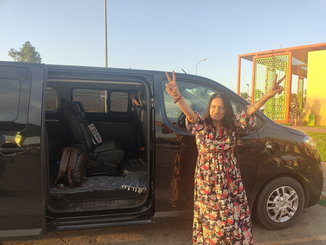 Woman posing with a van in a parking area.