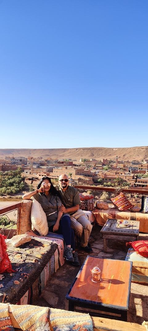 Couple smiling with a townscape and desert hills in the background.