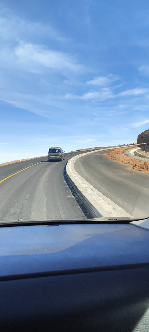 Car driving on a winding road in a desert.