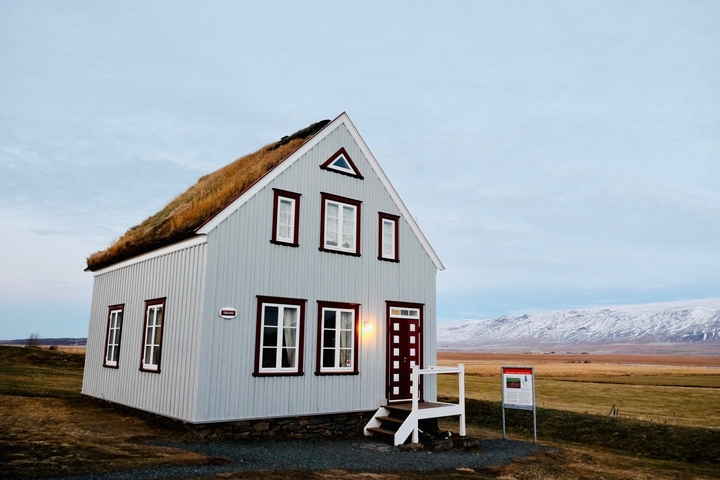 Traditional Icelandic house with a grassy roof in a rural setting.