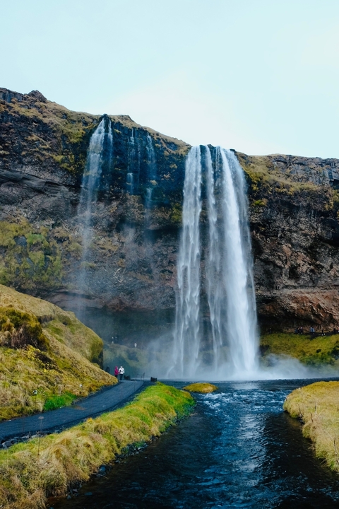 Majestic waterfall cascading over a rocky edge surrounded by greenery.