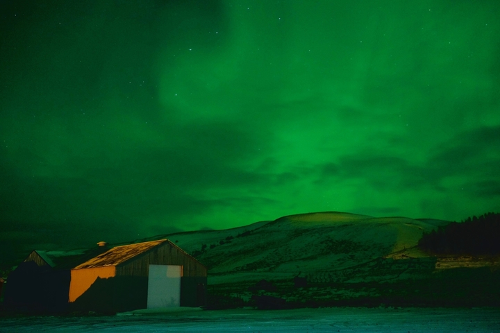 Stunning view of the Northern Lights illuminating the night sky over a rural landscape.