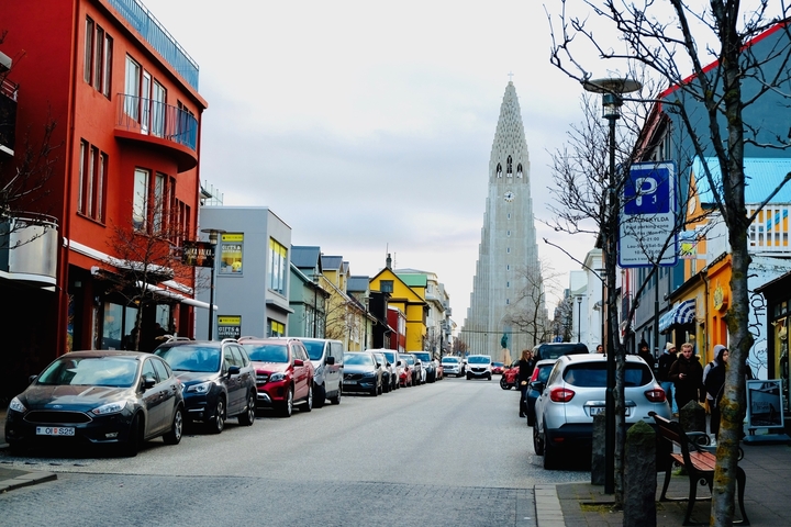Urban street scene with colorful buildings and distant church spire.