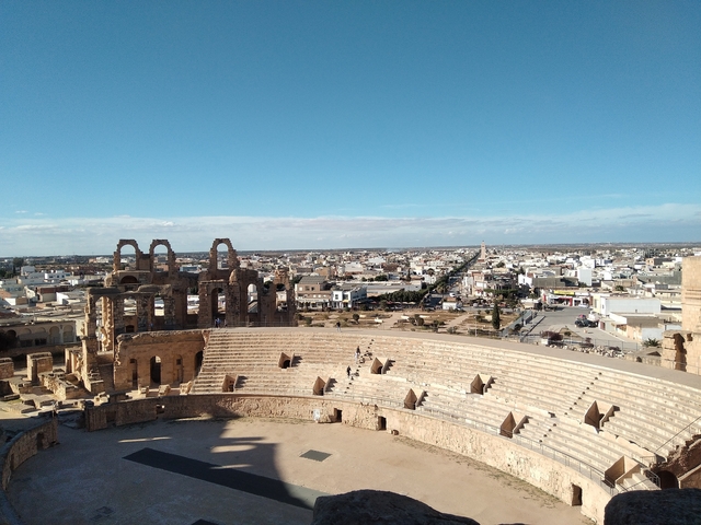 View of an ancient amphitheater with city in the background.