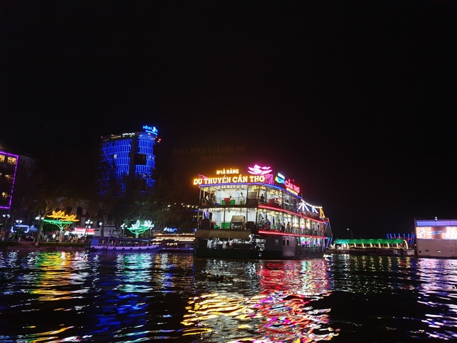 A brightly lit cruise boat on a river at night.