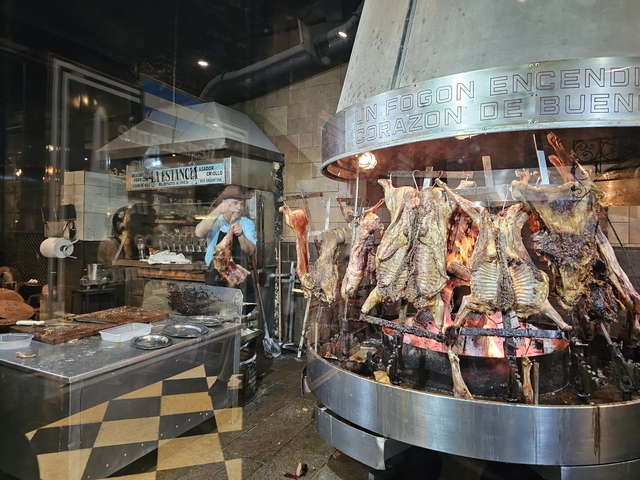 Open fire grill with various meats cooking in a traditional restaurant.