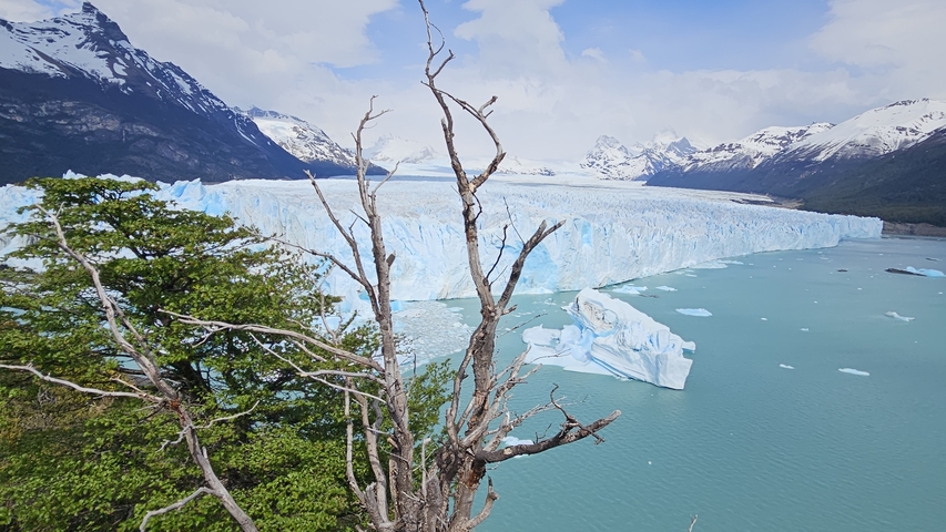 Huge glacier extending into a lake with mountains