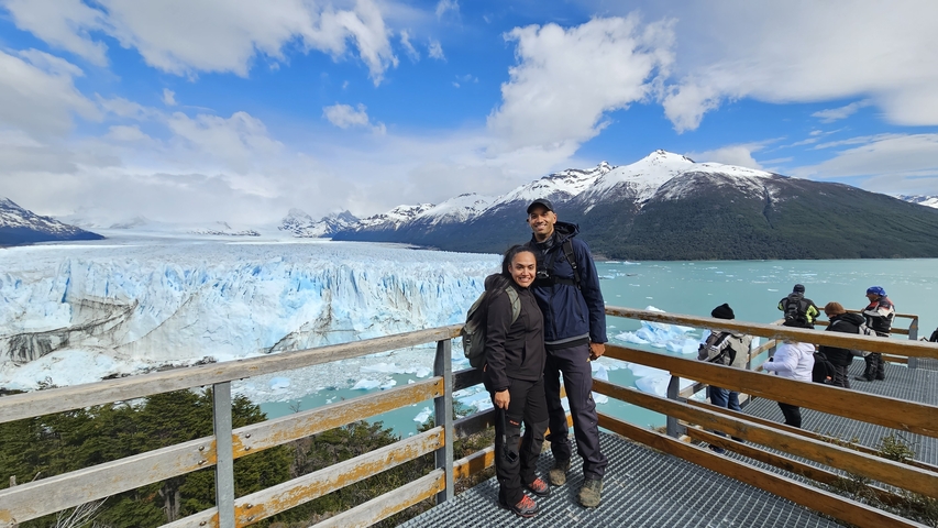 Couple standing on a view deck with glacier in the background