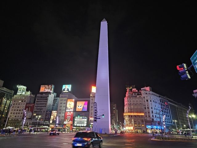 Obelisk lit up at night surrounded by city lights.
