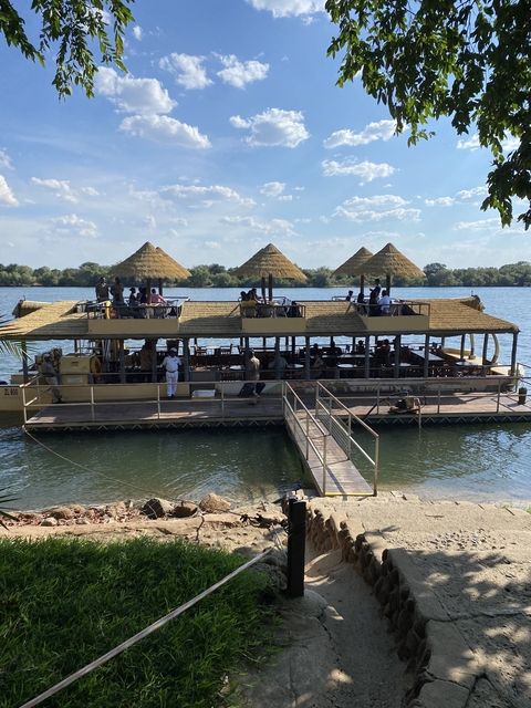 Tourists on a boat with thatched roofs on the water.
