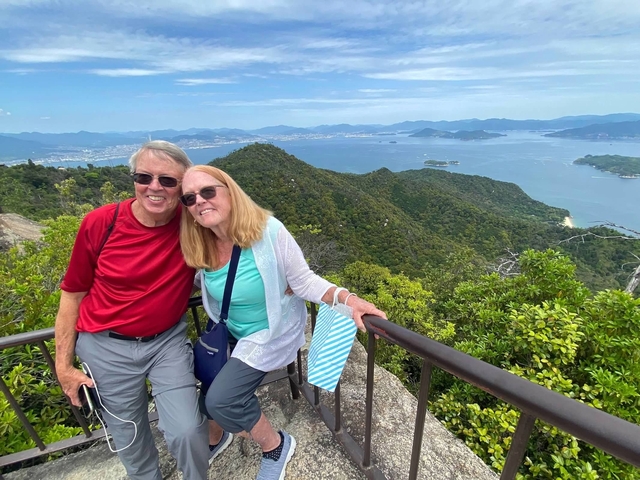 Couple posing with a scenic mountainous landscape in the background.