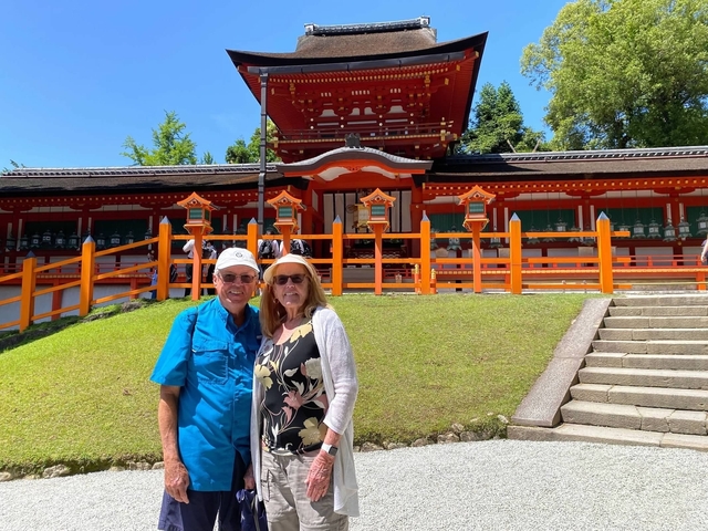 Couple posing in front of a traditional Japanese shrine with orange gate.