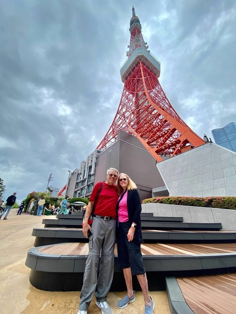 Couple posing near Tokyo Tower with other visitors around.