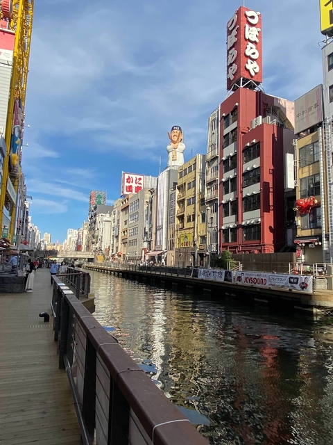 Sunny day at a historic canal with retro buildings and signage.