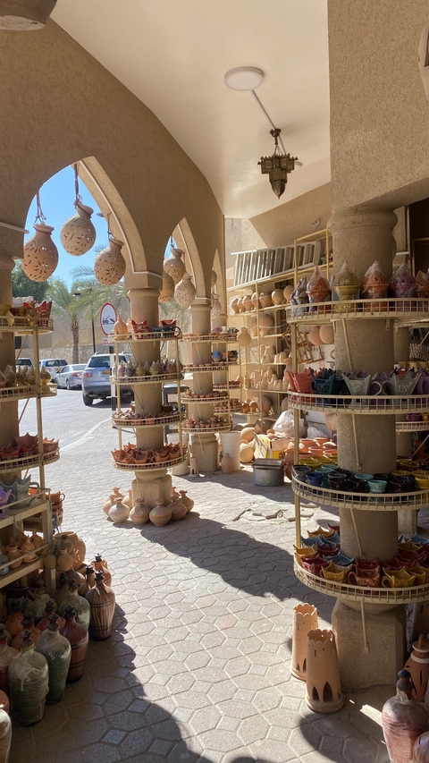 Bustling market with colorful pottery on display.