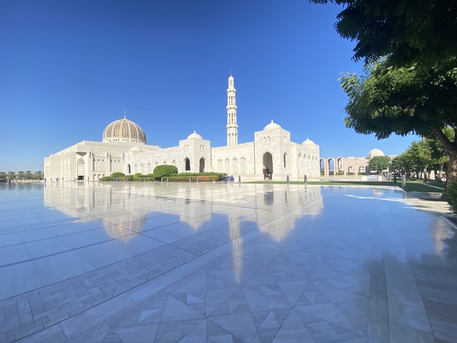 Beautiful mosque with a tall minaret reflected on polished ground.