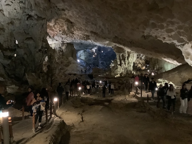 Visitors exploring a large illuminated cave.
