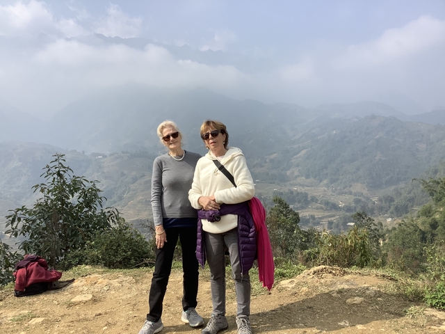 Two people posing with a scenic mountainous landscape.