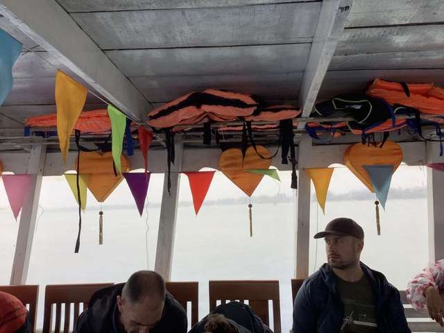 Interior of a boat with colorful decorations and passengers.