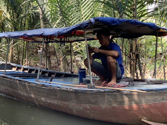 Person on a boat in a lush, green waterway.
