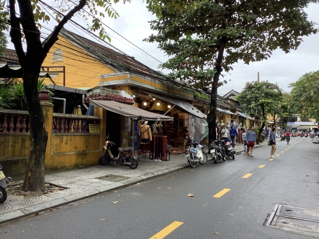 Street in a market area with shops and motorcycles.