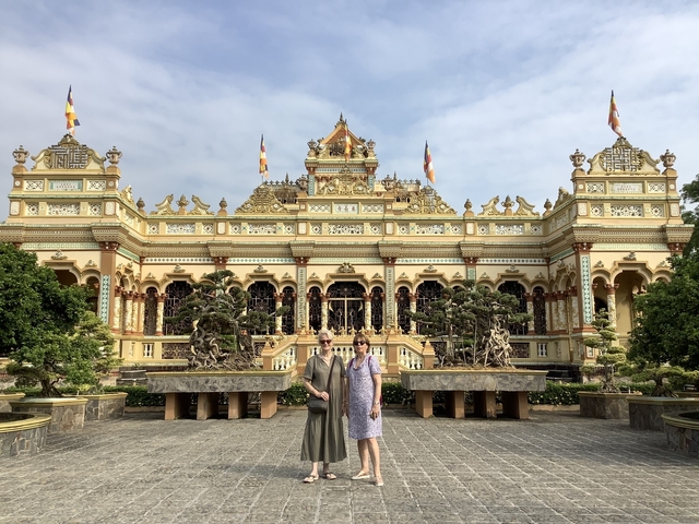 Two people standing in front of a decorative temple.