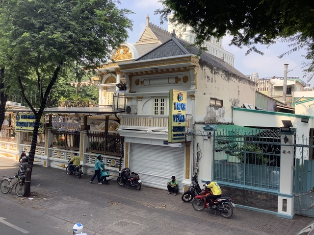 Street view of a building with motorbikes and people around.