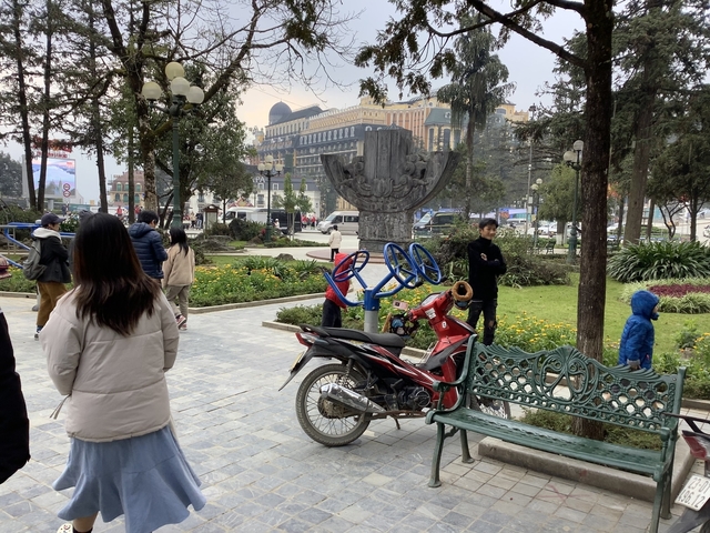 Public square with people walking and benches.