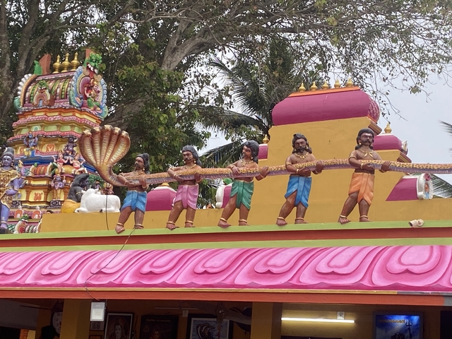 Vibrant temple facade with figures in bright clothing holding serpents.