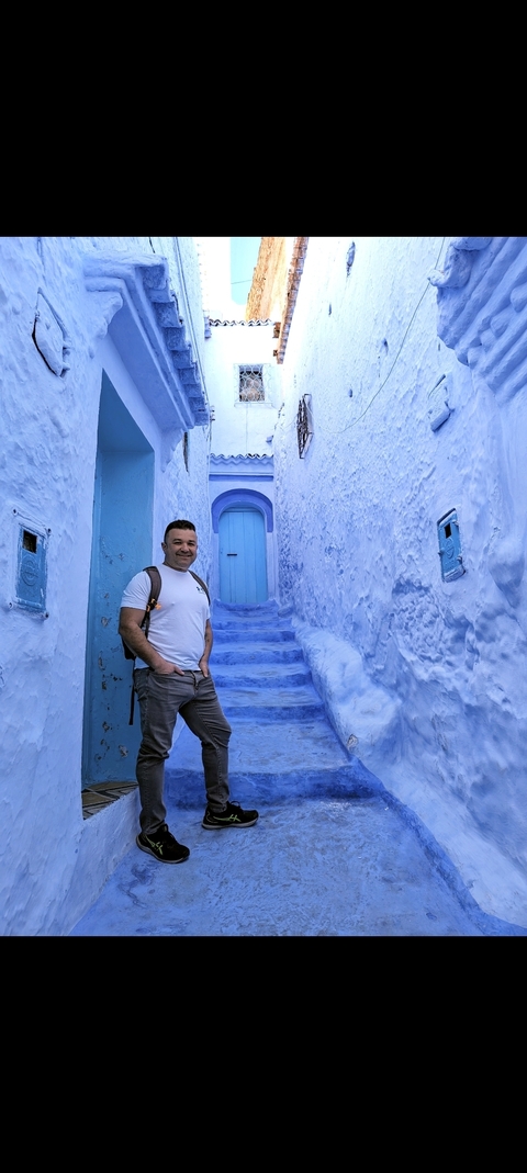 Man standing in the famous blue-painted street in Chefchaouen.