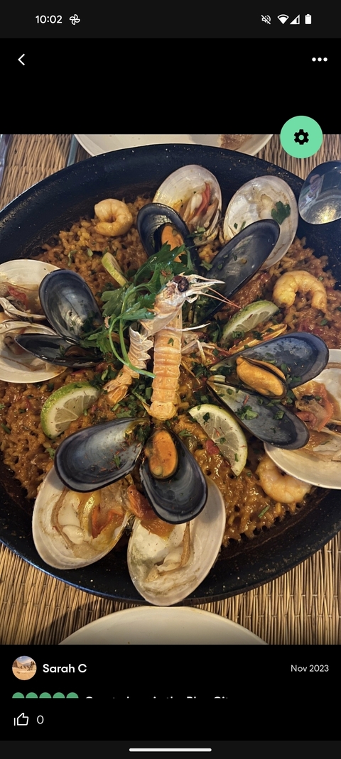Seafood paella dish topped with mussels and garnished with lime.