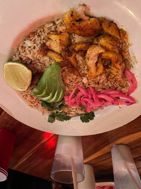 Plate of rice with grilled chicken and avocado.