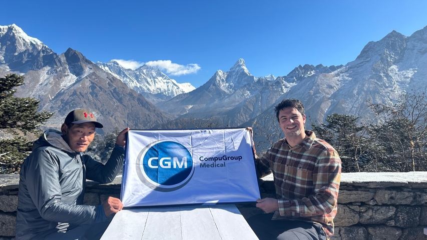 Two people holding a banner with mountains in the background.