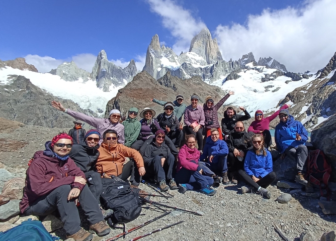Group of trekkers posing in front of snow-capped mountains.