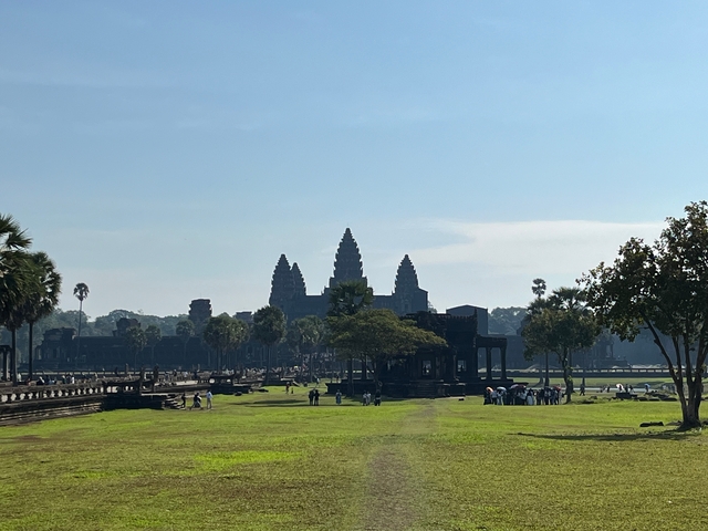 View of Angkor Wat with grass and trees in the foreground.
