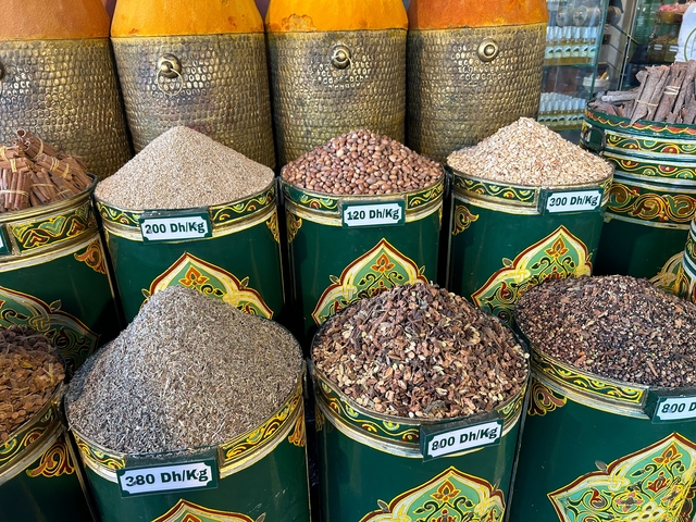 Containers filled with various spices at a market stand.