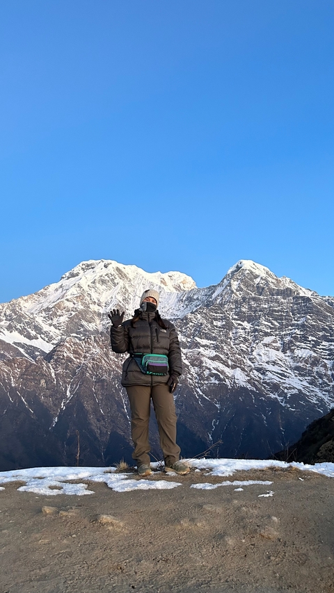 Person posing with snowy mountain backdrop.