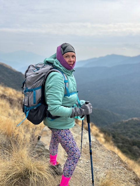 Hiker with backpack posing on a mountain trail.