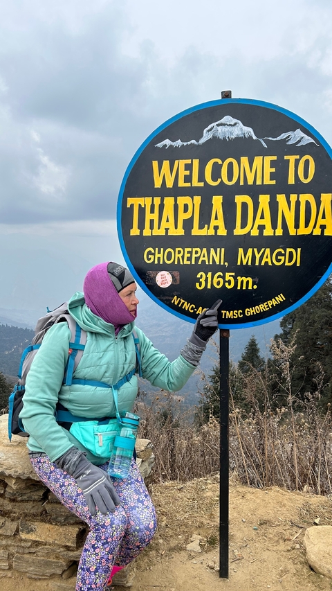 Hiker pointing to a sign at high altitude.