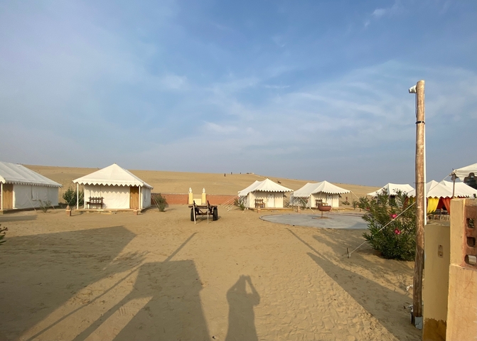 Desert campsite with tents arranged in a circle under a clear sky.