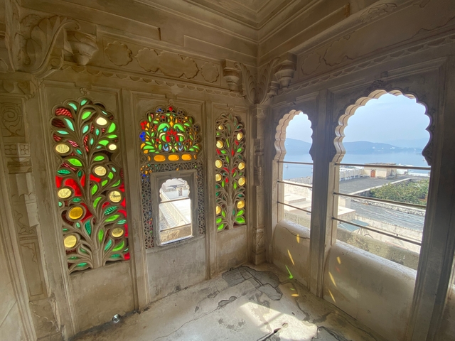 Interior of a palace with colorful stained glass windows and stone carvings.
