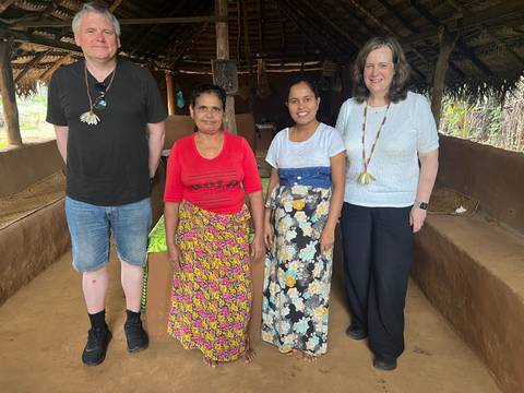 A group of tourists posing with local people in a traditional setting.