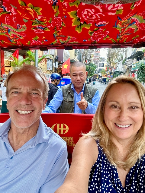 A couple enjoying a rickshaw ride with a thumbs-up driver.