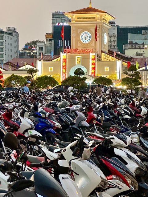 Crowded parking area filled with motorbikes at night.