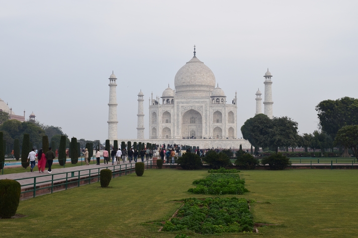 The Taj Mahal in Agra with a group of people walking in the foreground.