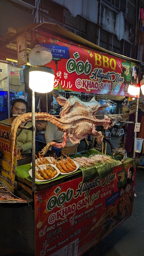 Street food vendor with various grilled foods displayed.